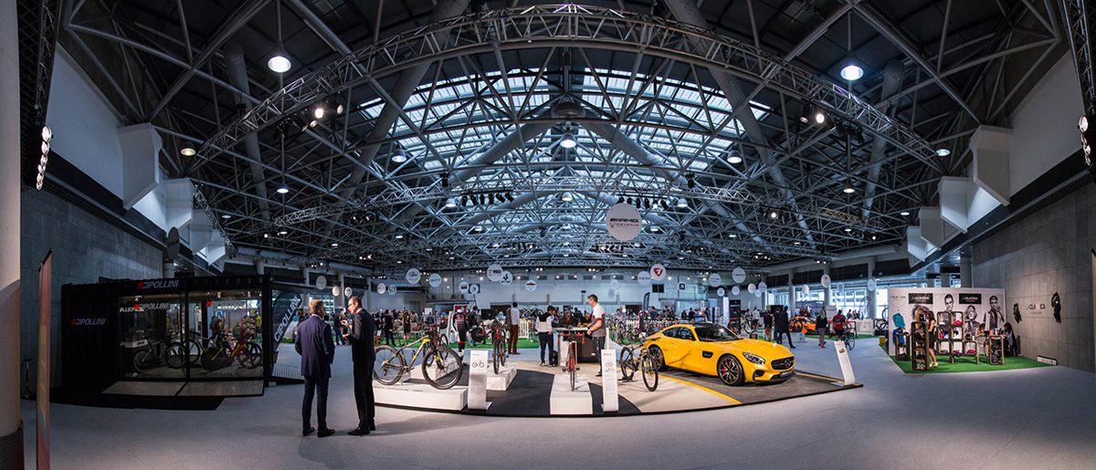 A group of people standing around cars in an indoor setting.