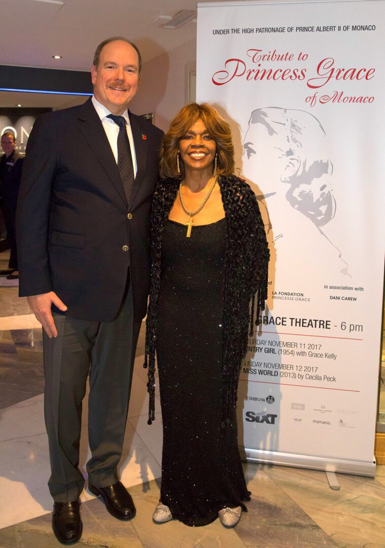 A man and woman standing in front of a poster.